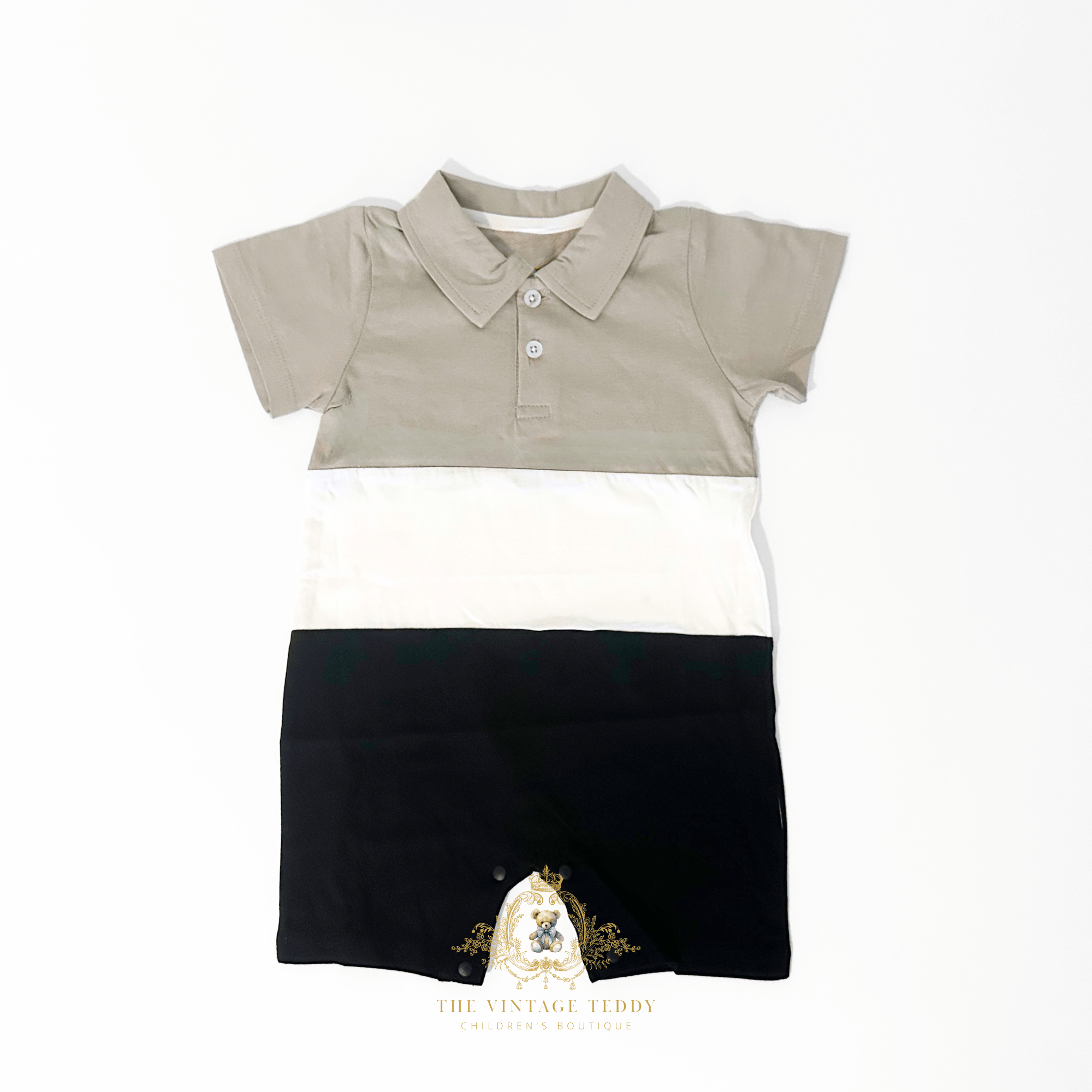 A children's short-sleeve polo shirt one-piece bodysuit laid flat on a white background, featuring color-blocked sections of taupe, white, and black, with a small buttons and pointed collar.
