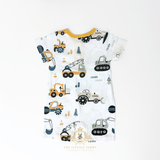 The back of a white short-sleeve baby one-piece with an all-over construction vehicle print, featuring yellow, green, and gray bulldozers, tractors, and excavators. The baby romper is laid flat on a clean white background with a The Vintage Teddy's  watermark at the bottom.