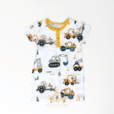 A baby short-sleeve romper with an all-over construction vehicle print on a white background, featuring a yellow collar and yellow snap buttons. The print includes orange, yellow, green, and black colors.