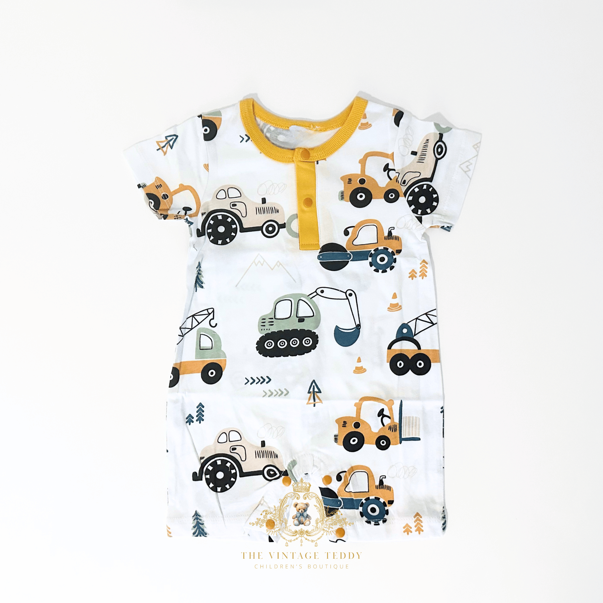 A baby short-sleeve romper with an all-over construction vehicle print on a white background, featuring a yellow collar and yellow snap buttons. The print includes orange, yellow, green, and black colors.