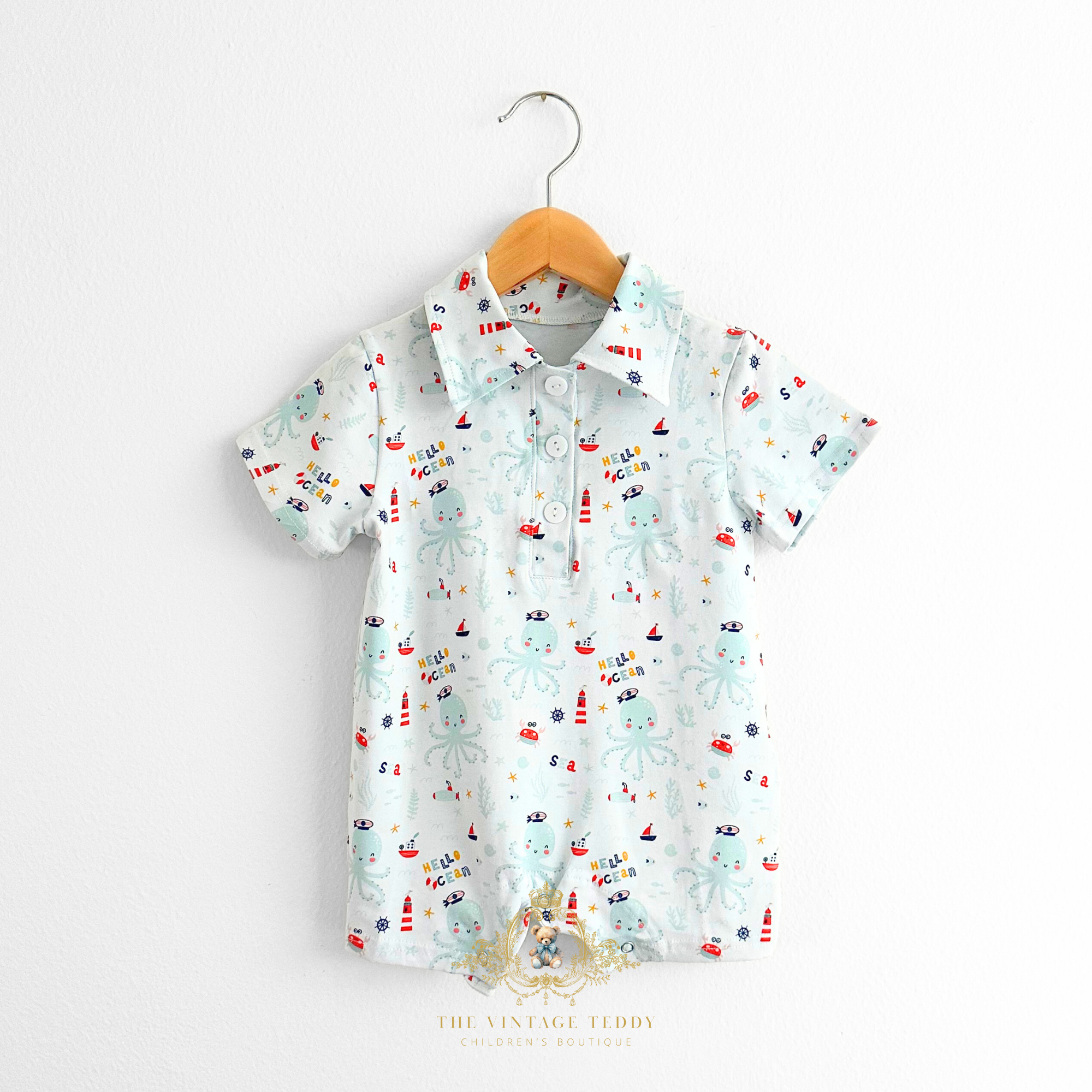 Baby romper with colorful ocean-theme pattern on a hanger against a white background The Vintage Teddy Children's Boutique Cute Baby & Toddler Clothes for Kids