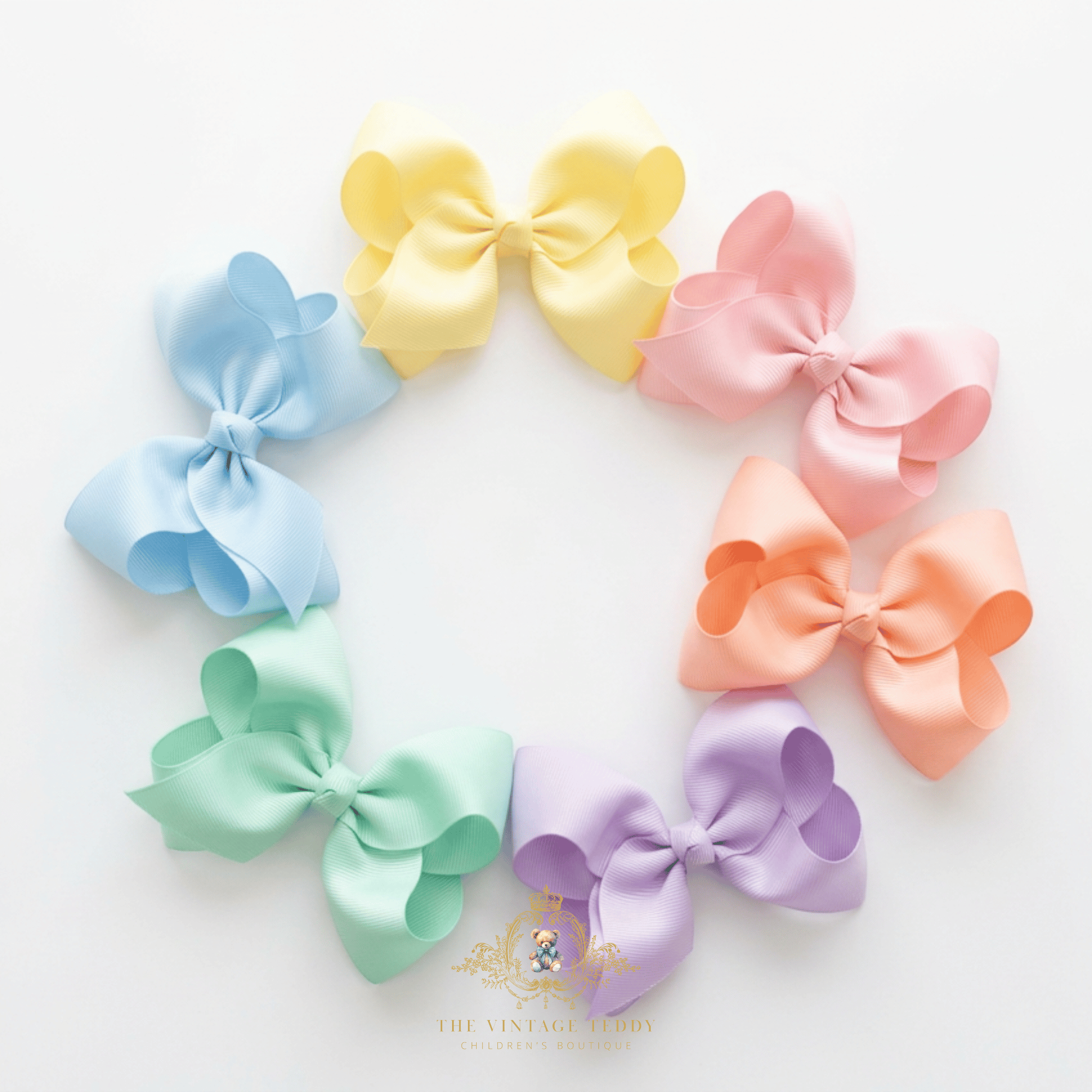 Six large grosgrain girls hair bows in pastel shades of yellow, baby blue, pink, peach, mint green, and lavender, arranged in a circle on a white background. The Vintage Teddy brand logo is bottom-center.