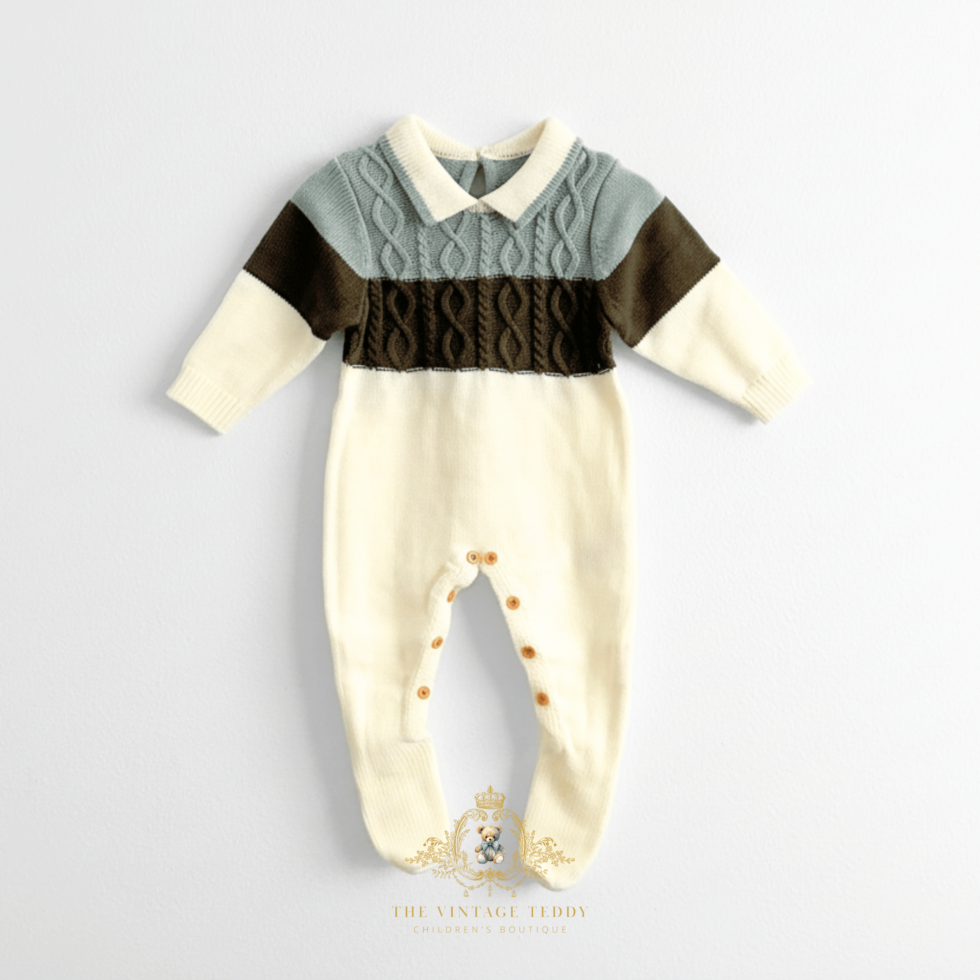 Baby boys knit footed jumpsuit with a color-blocked design. The top portion is a sage green cable-knit collar with a cream  collar, while the middle features a wide olive green band across the chest and sleeve stripe and the bottom is a cream color, laid flat on a white surface background.