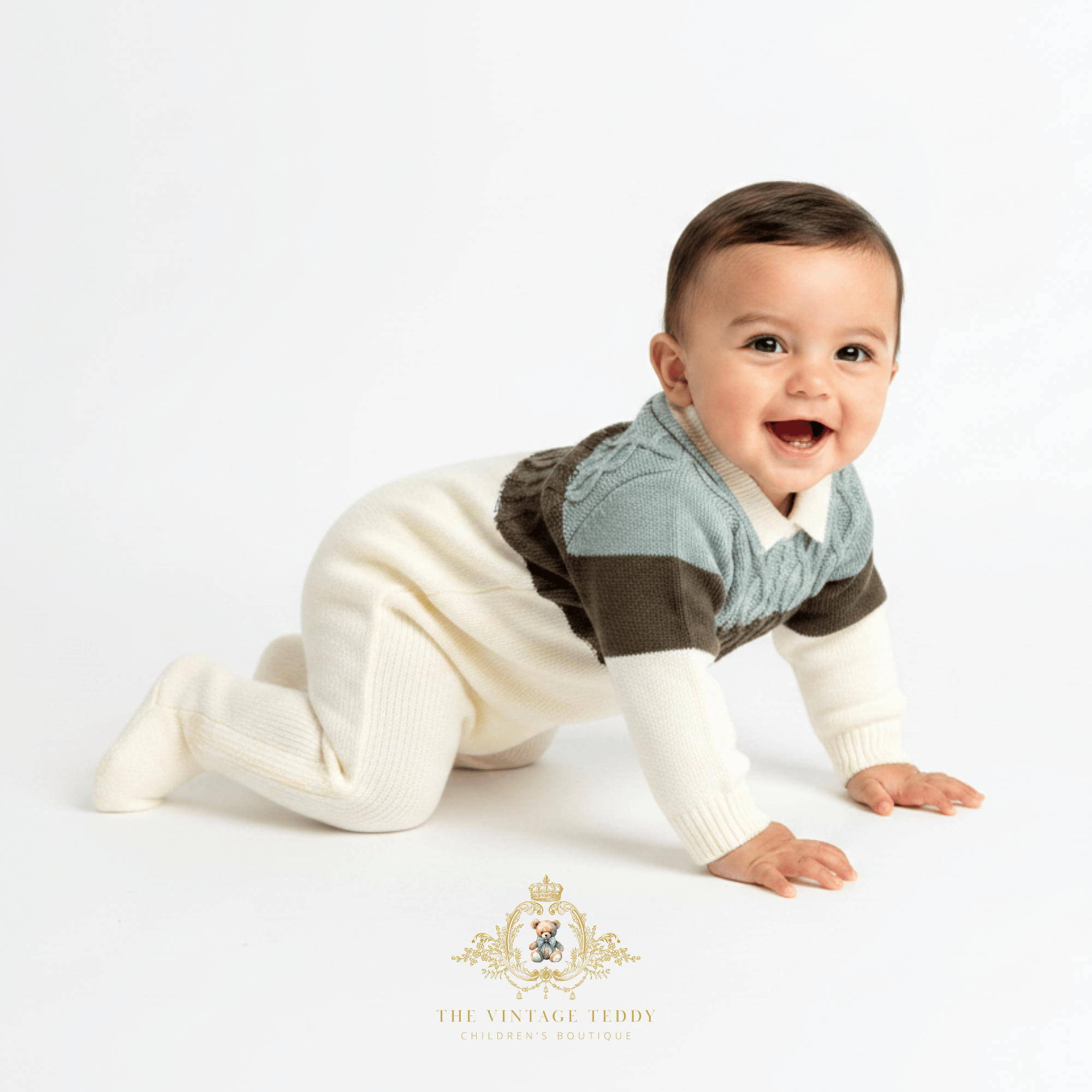 A baby crawling on a white studio floor wearing a cream, sage and olive green  knit footed one-piece. The brand logo 'The Vintage Teddy Clothing Boutique' is visible at the bottom.