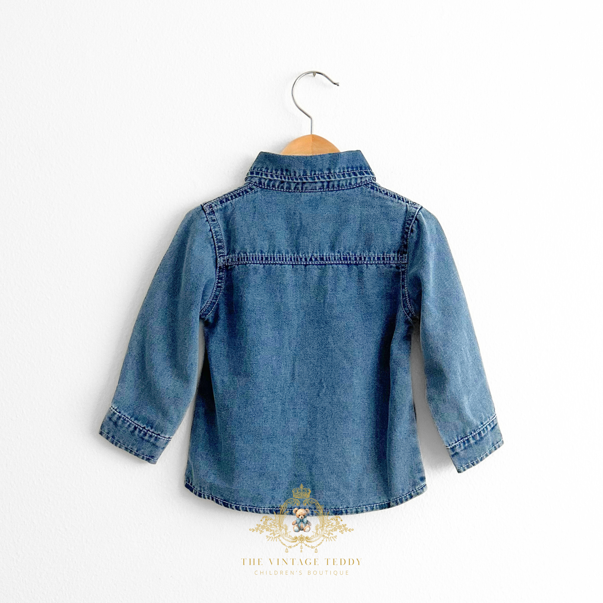 Boys blue denim kids shirt on a wood hanger with 'The Vintage Teddy' logo.