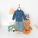 Cute children's boutique display featuring a denim outfit on a mannequin with a teddy bear, children's book and toys on a  white tabletop surface.