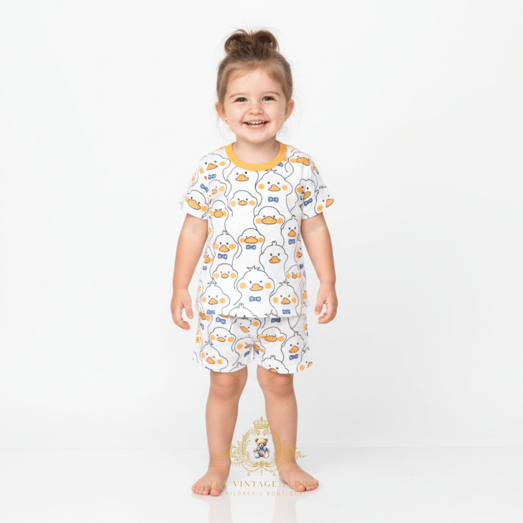 Toddler girl wearing Mr. Duck graphic t-shirt and shorts with all over print kids matching set yellow blue white kids clothes