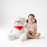 Toddler girl sitting with plush teddy bear, wearing Sweet Bear matching set, girls boutique summer outfit for kids