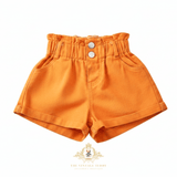 Bright orange high-waisted denim shorts for little girls with a buttoned waistband, displayed on a clean white background with The Vintage Teddy watermark at the bottom.