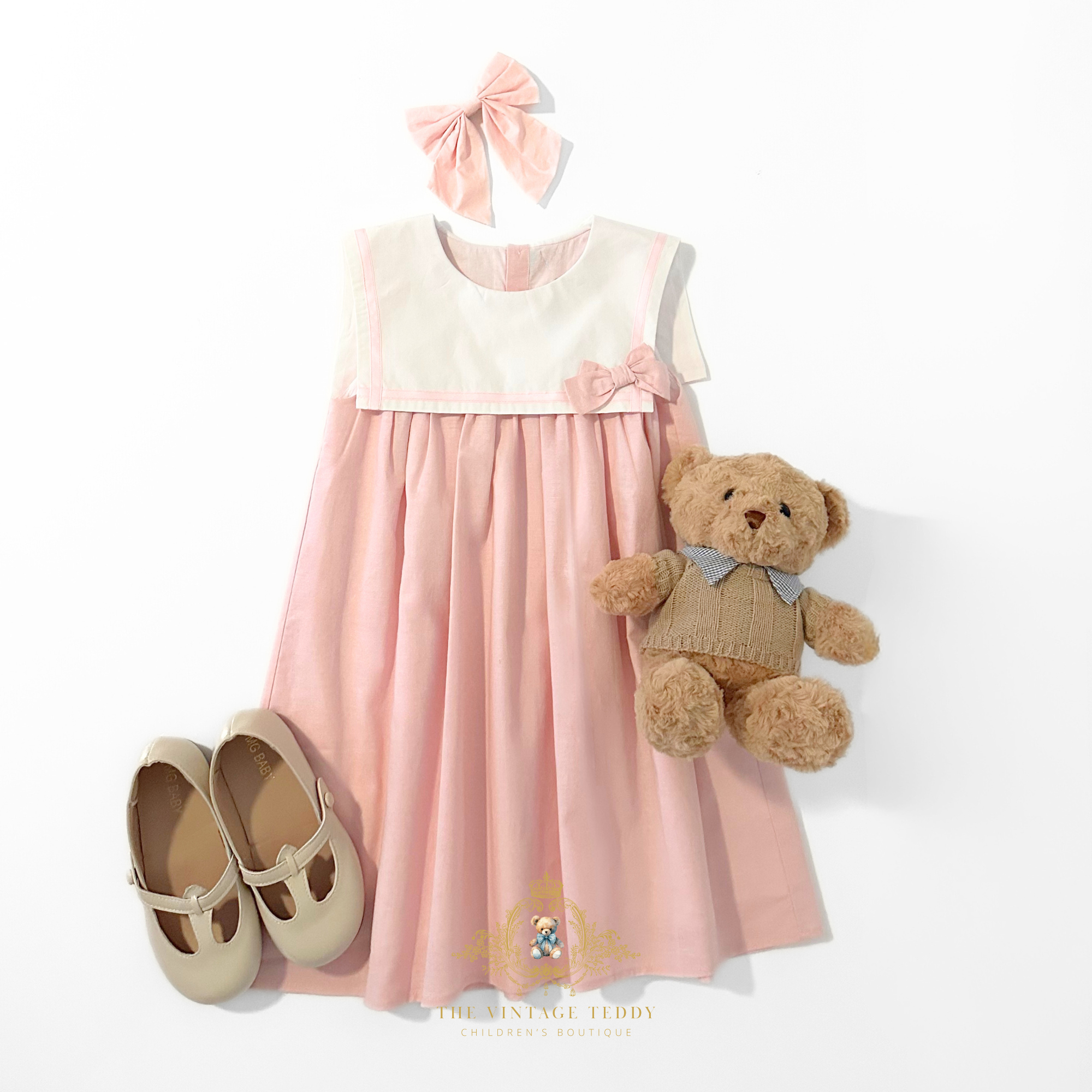 Girls pink sleeveless sailor dress with hair bow headband and plush doll table, top view – children's boutique kids clothes at The Vintage Teddy