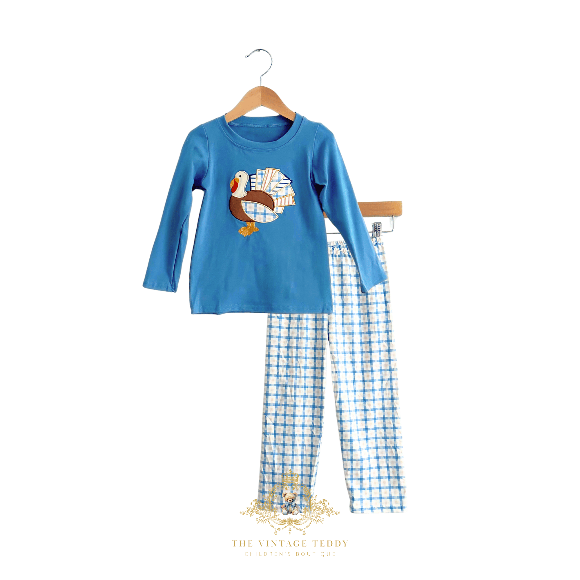 A children's two-piece top & bottom set on a hanger against a white background. The set includes a bright blue long-sleeve boys shirt with a turkey embroidery and matching blue-and-white checkered boys pants.