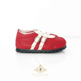 A red leather toddler sneaker with two white straps and silver buckles, shown from the side on a white background with a brand watermark at the bottom.