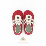 A pair of red faux-leather kids shoes with white-colored straps, shown from a top-down view on a white background with a The Vintage Teddy brand watermark at the bottom.