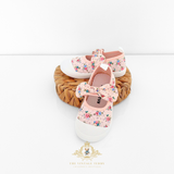 Cute pair of floral baby shoes displayed on a woven basket.
