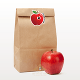 Brown paper bag with a red apple and a smiley face sticker for kids with an apple a day saying on a white background