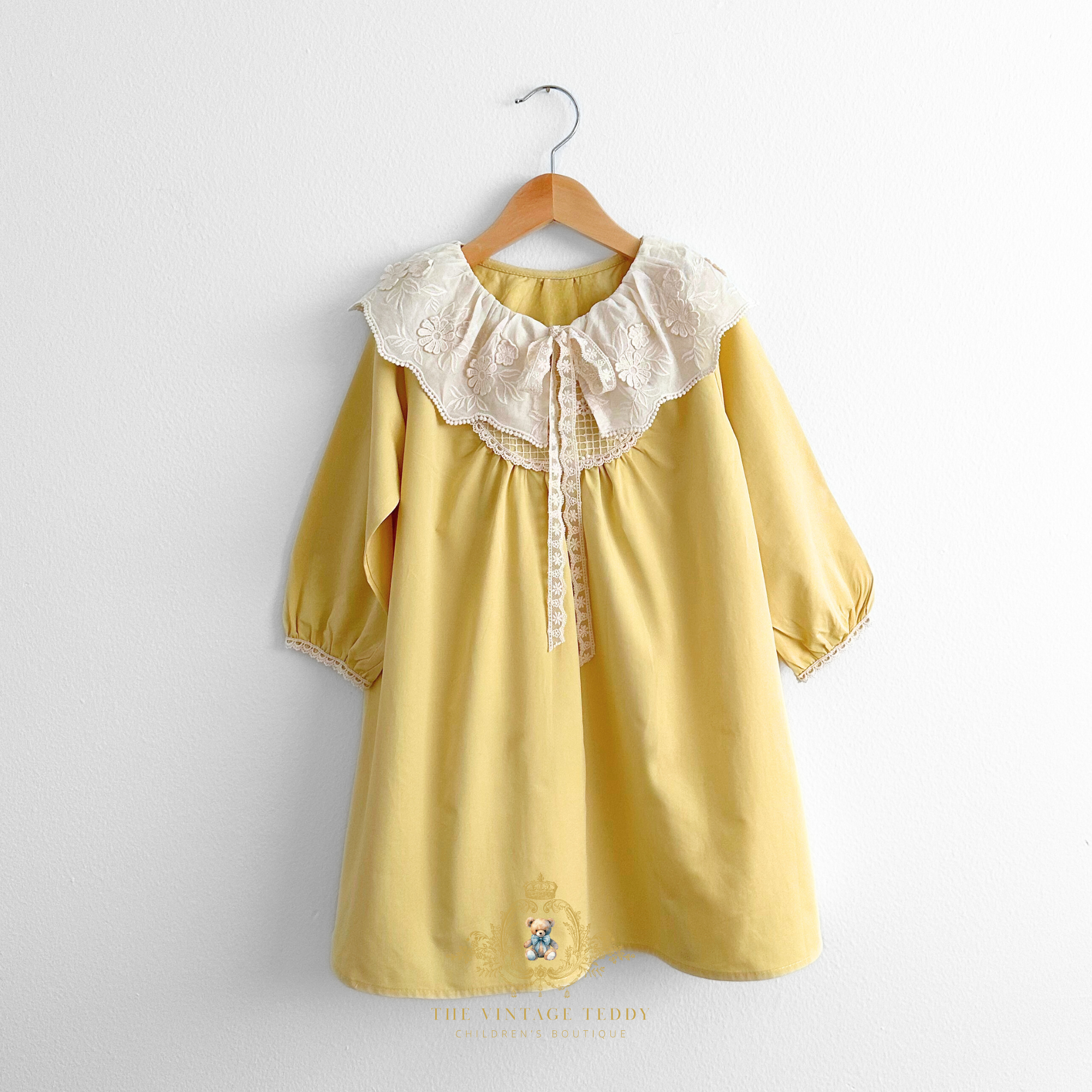 Pretty yellow girls dress long sleeves with scalloped  lace peasant collar on a hanger against a white background, find girls modest dresses at The Vintage Teddy Children's Boutique.