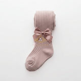 A single ribbed knit kids sock or girls stocking in a dusty mauve-pink color, featuring a matching fabric bow displayed on a clean white background.