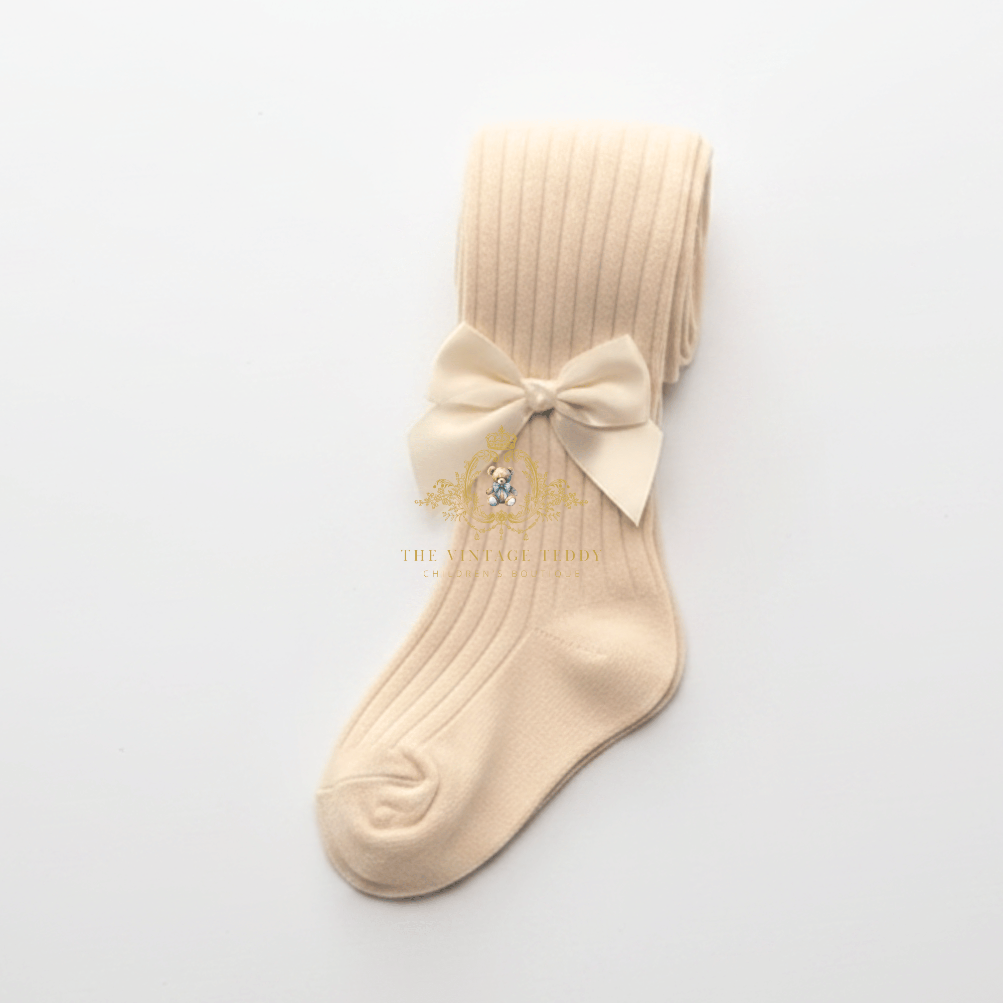 A cream color ribbed knit kids stockings or toddler girls sock with a matching cream  satin bow displayed on a clean white background.