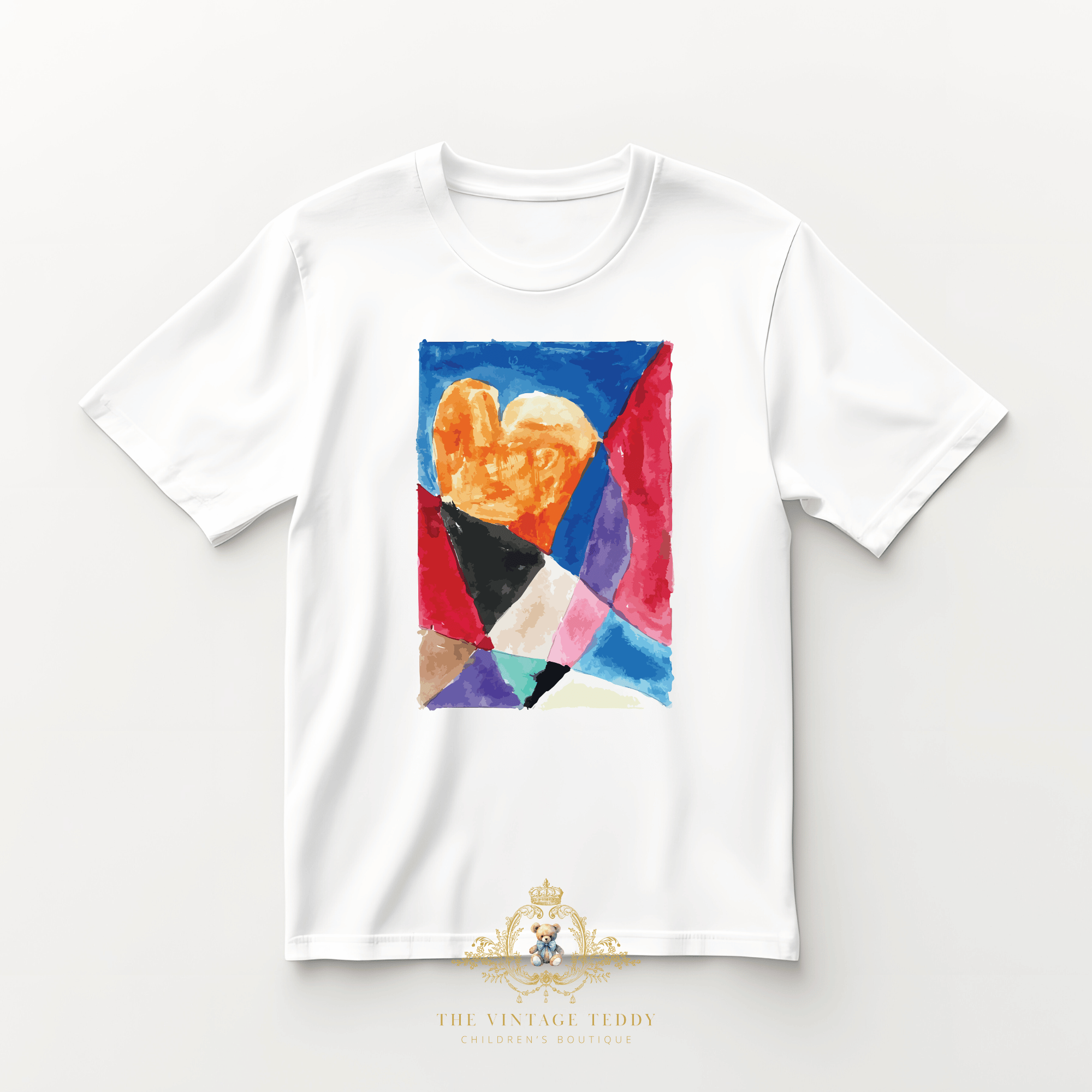 Flat lay of a children's white t-shirt with a custom colorful stain glass watercolor artwork, an abstract heart is in the center, on a light studio background surface. The Vintage Teddy's logo is visible at the bottom of the image.