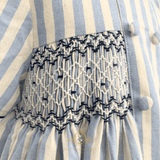 Close-up of a blue and cream striped fabric garment, kids smocked dress with a smocked waistband in white and navy blue.