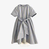 The back of a short-sleeve children's dress with vertical blue and beige stripes, featuring a bow at the back and a ruffled collar, shown against a light background.
